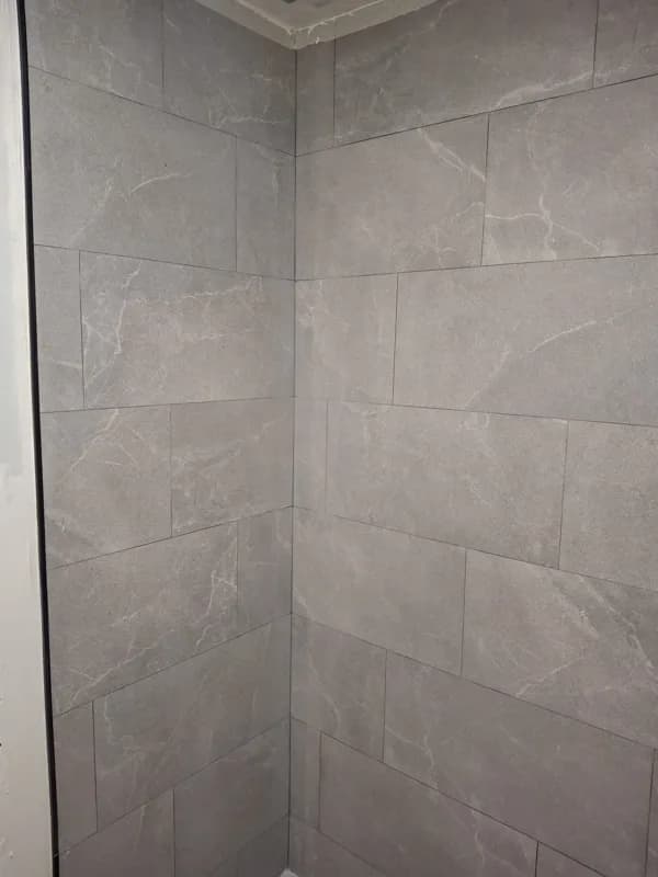 Ducha alicatada en porcelánico gris con esquinas perfectamente rematadas — Junior Reformas