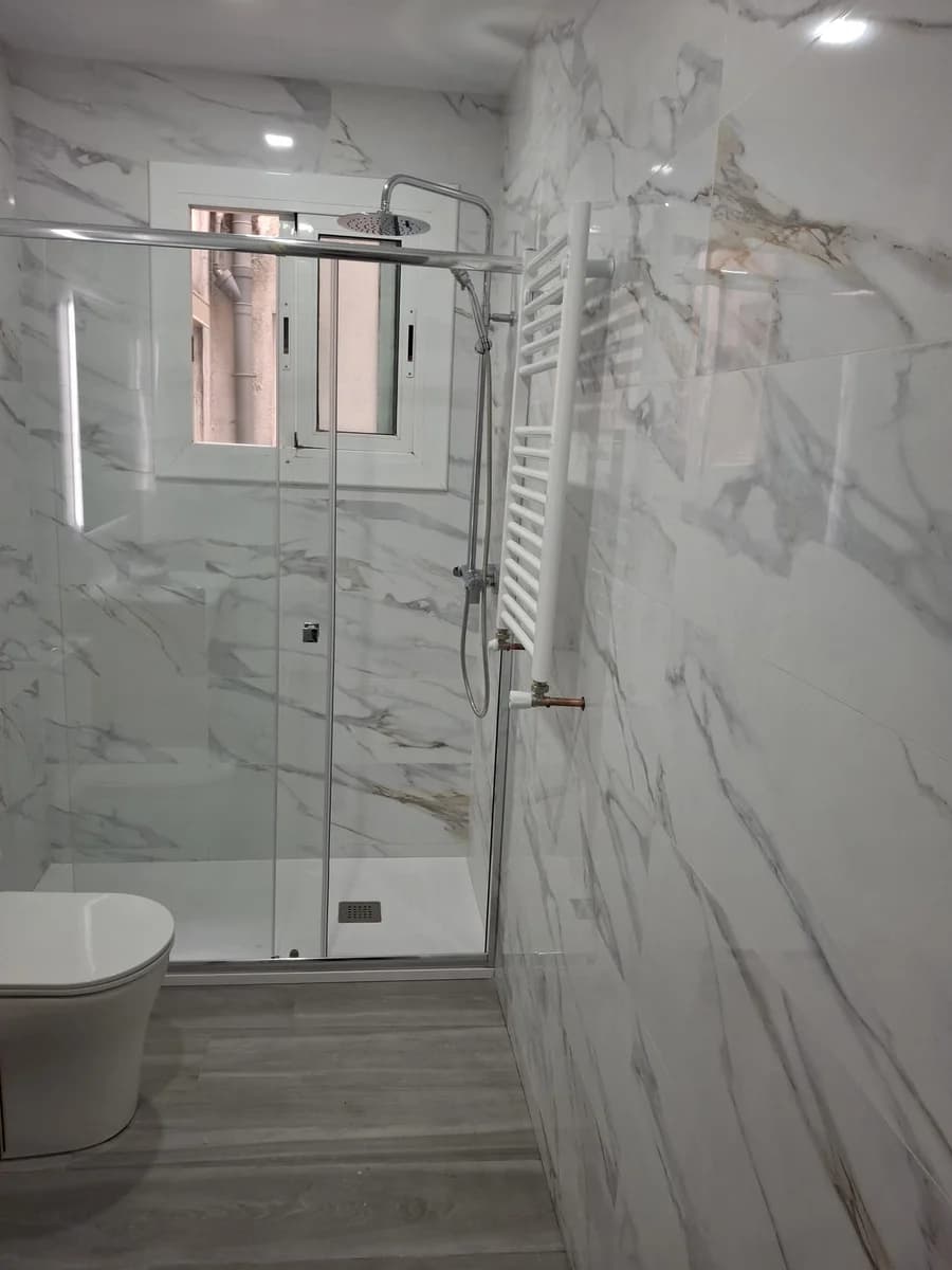 Baño terminado: baño mármol ducha inodoro — Junior Reformas