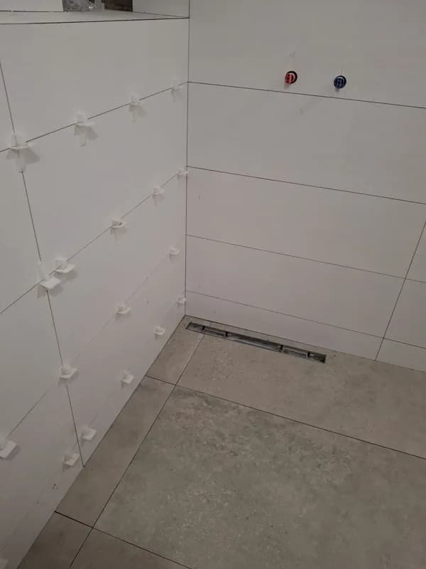 Baño en fase de alicatado con desagüe lineal en suelo — Junior Reformas
