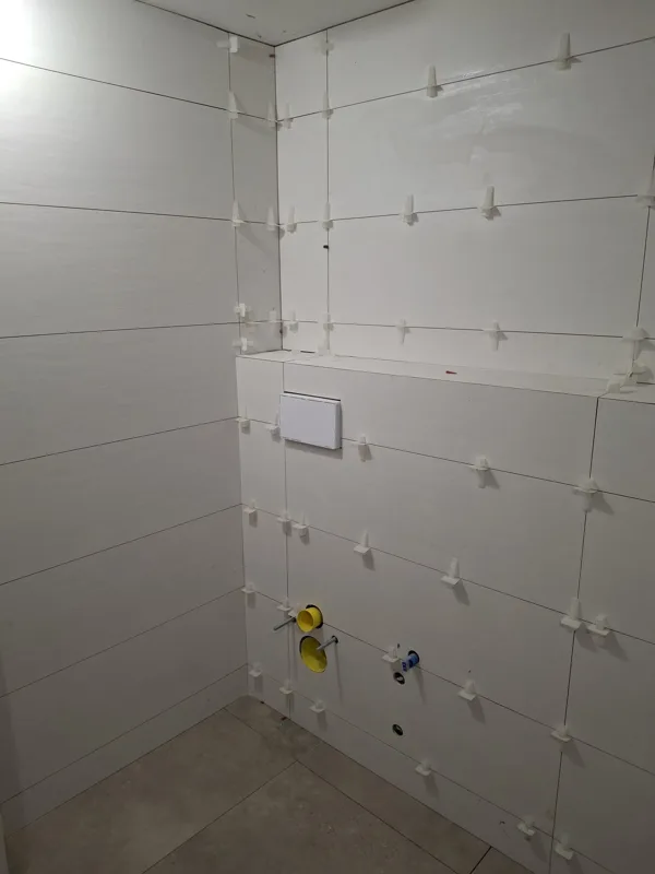Esquina de baño alicatada en blanco durante la obra — Junior Reformas