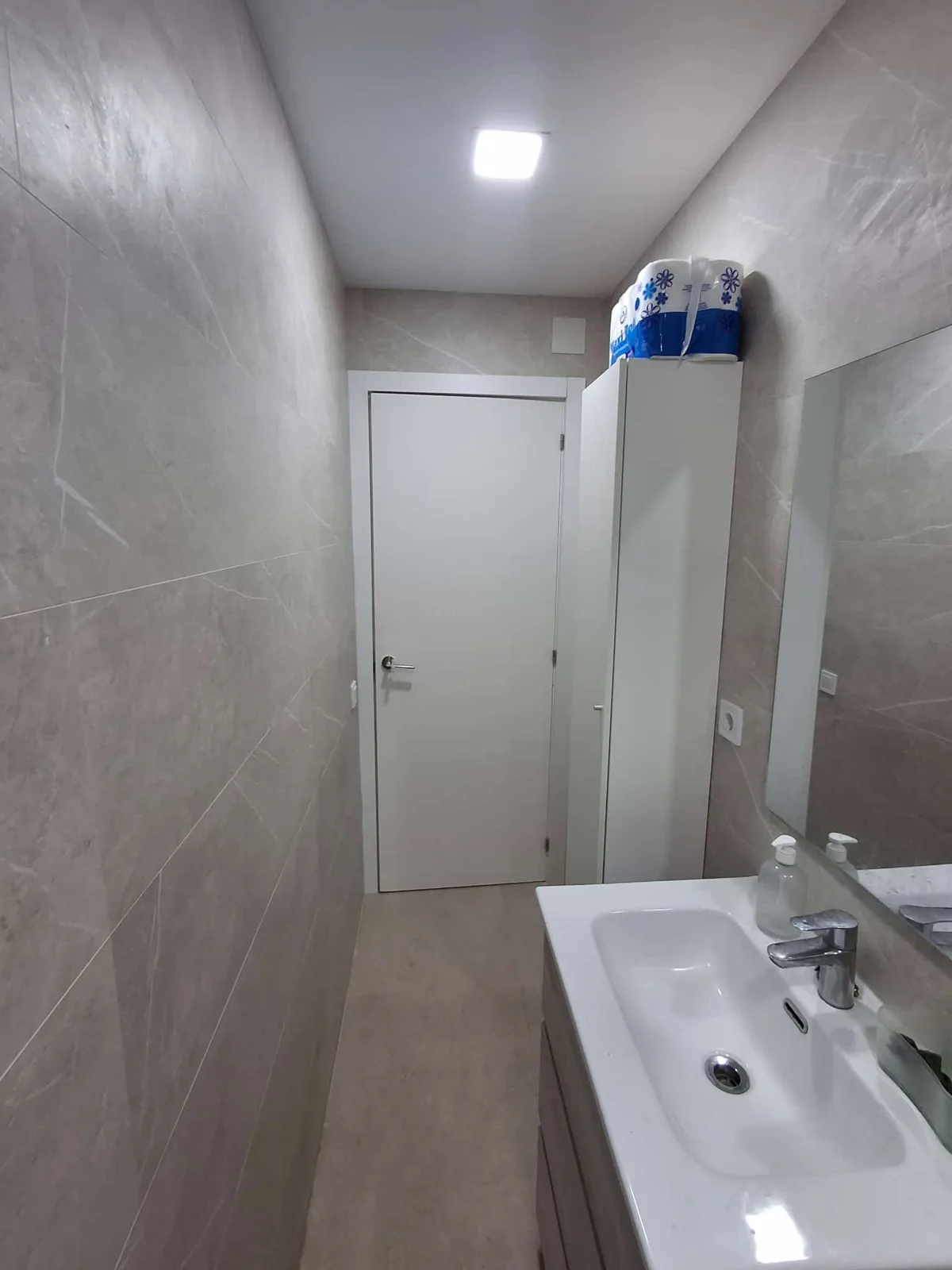 Baño completo reformado con revestimiento gris y radiador toallero — Junior Reformas