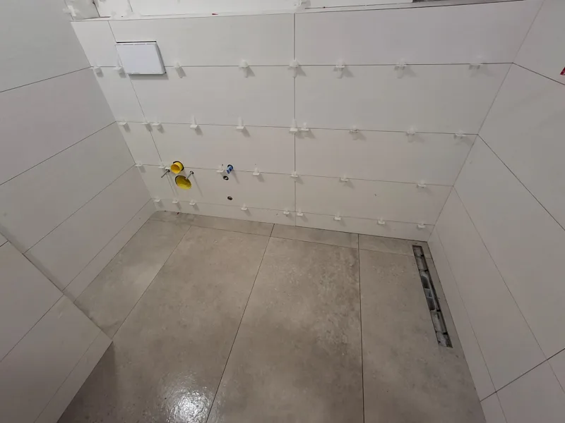 Transformación de ducha: alicatado en obra y acabado final en porcelánico gris — en obra